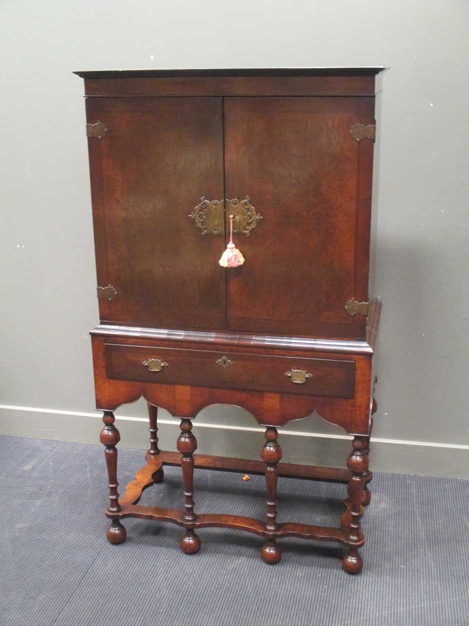 An 18th century style crossbanded walnut cabinet on stand, the two doors over a single long drawer
