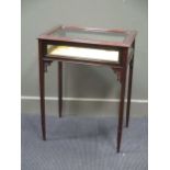 A mahogany glazed top display table with carved top