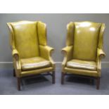A pair of George III style green leather upholstered wingback arm chairs (2)