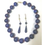 A row of lapis lazuli and ruby beads with earpendants en suite,