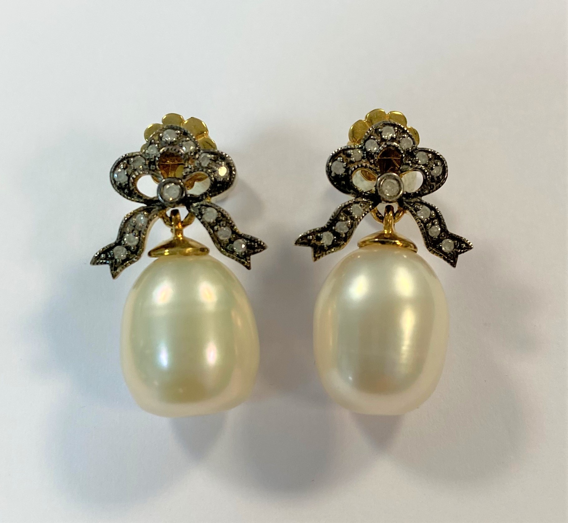 A pair of cultured pearl and diamond bow earpendants,