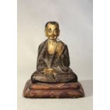 A Tibetan painted wood seated figure of a monk, 18th/19th century,