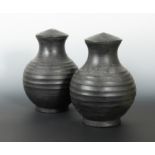 A pair of Chinese burnished pottery lidded vases, with deeply ribbed bodies, perhaps Han Dynasty,
