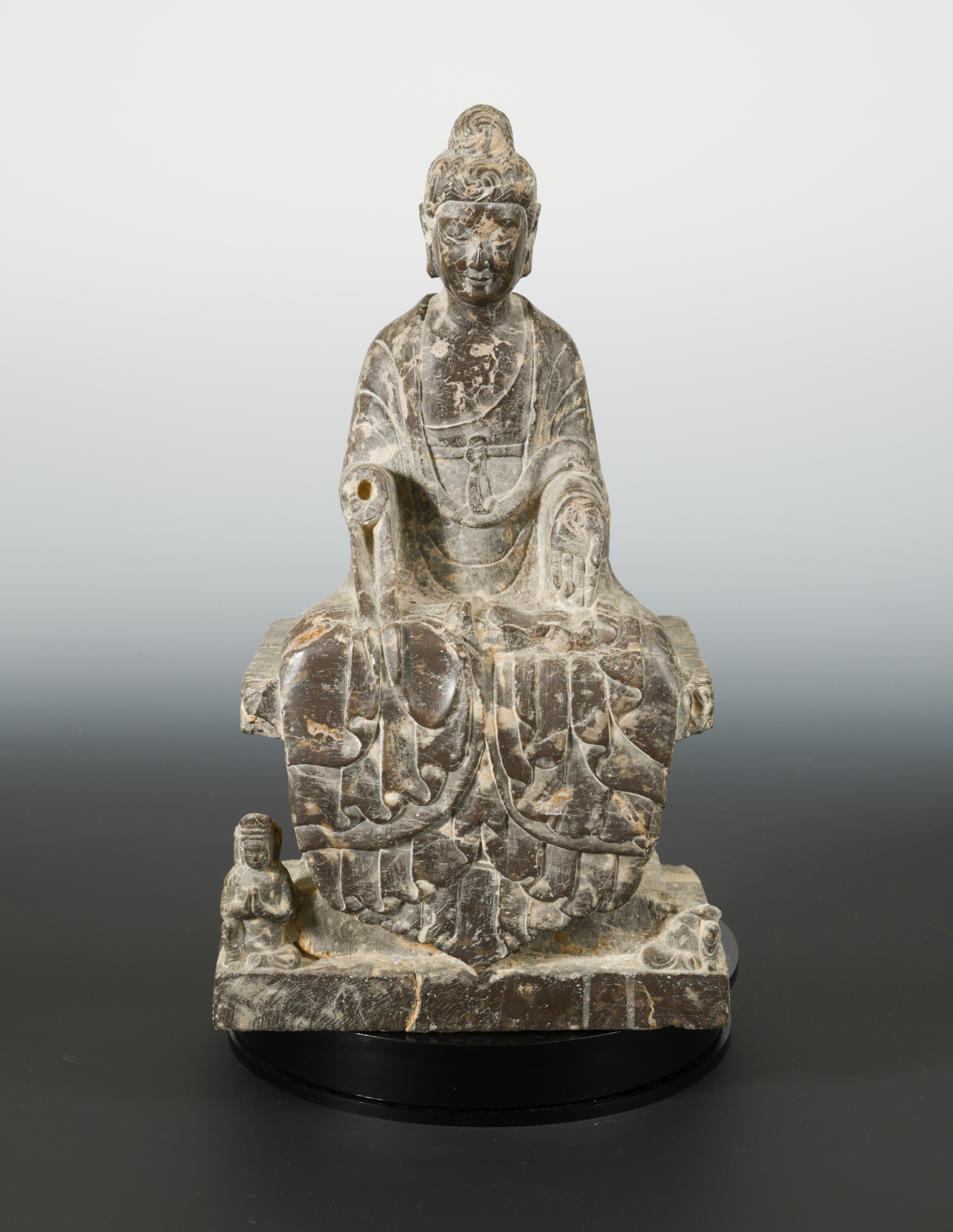 A Chinese mottled dark stone seated Buddhist deity, in Wei Dynasty style,