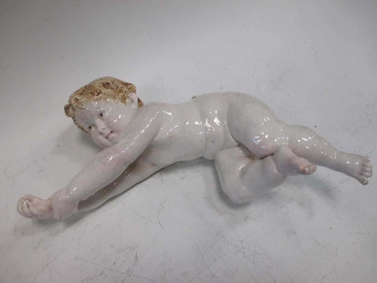 A continental porcelain model of a cherub, 33cm long