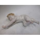 A continental porcelain model of a cherub, 33cm long