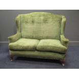 An early 20th century green upholstered two seater wing back settee 103cm high 126cm wide and 73cm