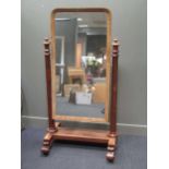 An early Victorian mahogany cheval mirror, the rounded rectangular mirror supported on pillars,