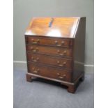 A George III style mahogany bureau with fitted interior over four graduating long drawers on bracket