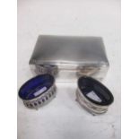 A silver table cigarette box, a silver salt by Asprey with blue glass liner, and another salt with a