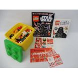 A Lego plastic container, full of loose Lego, plus various Lego stickers and a sticker book.
