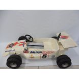 A 1970s plastic pedal car in the form of a Formula 1 racing car, covered in period decals
