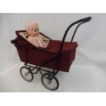 A small doll's pram containing a doll.