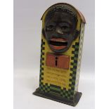 A rare German tinplate money box depicting a native African sticking his tongue out, advertising