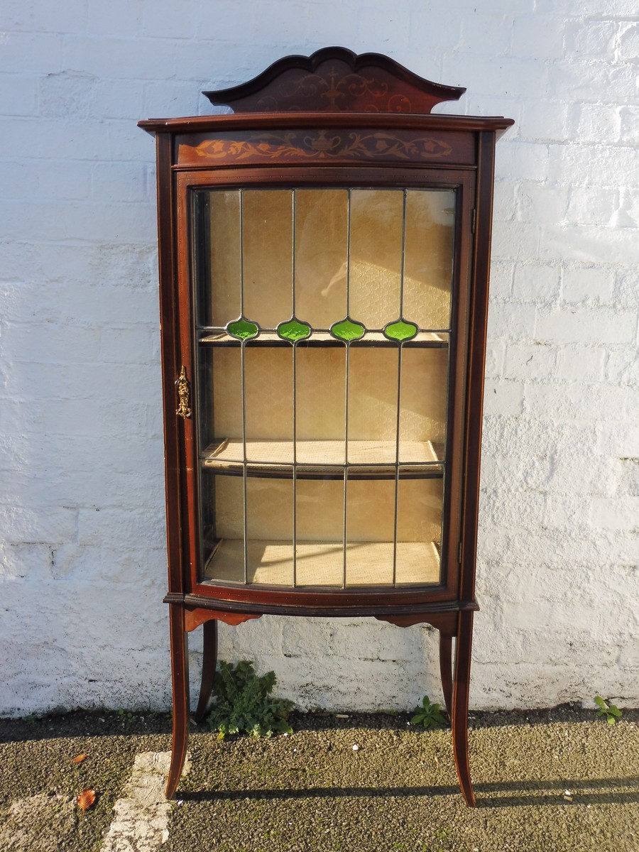 An Edwardian inlaid mahogany bow fronted display cabinet with stained glass leaded panel.