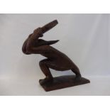 An unusual chip carved mahogany sculpture of a figure holding a block above his head, possibly Inuit