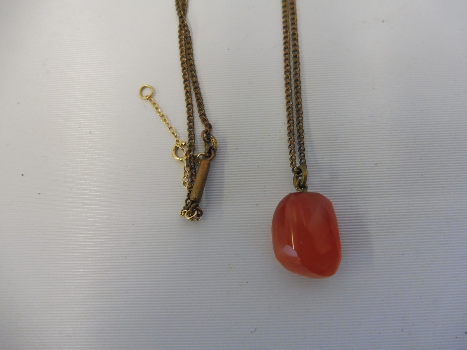 A Cornelian pendant on a yellow metal chain.