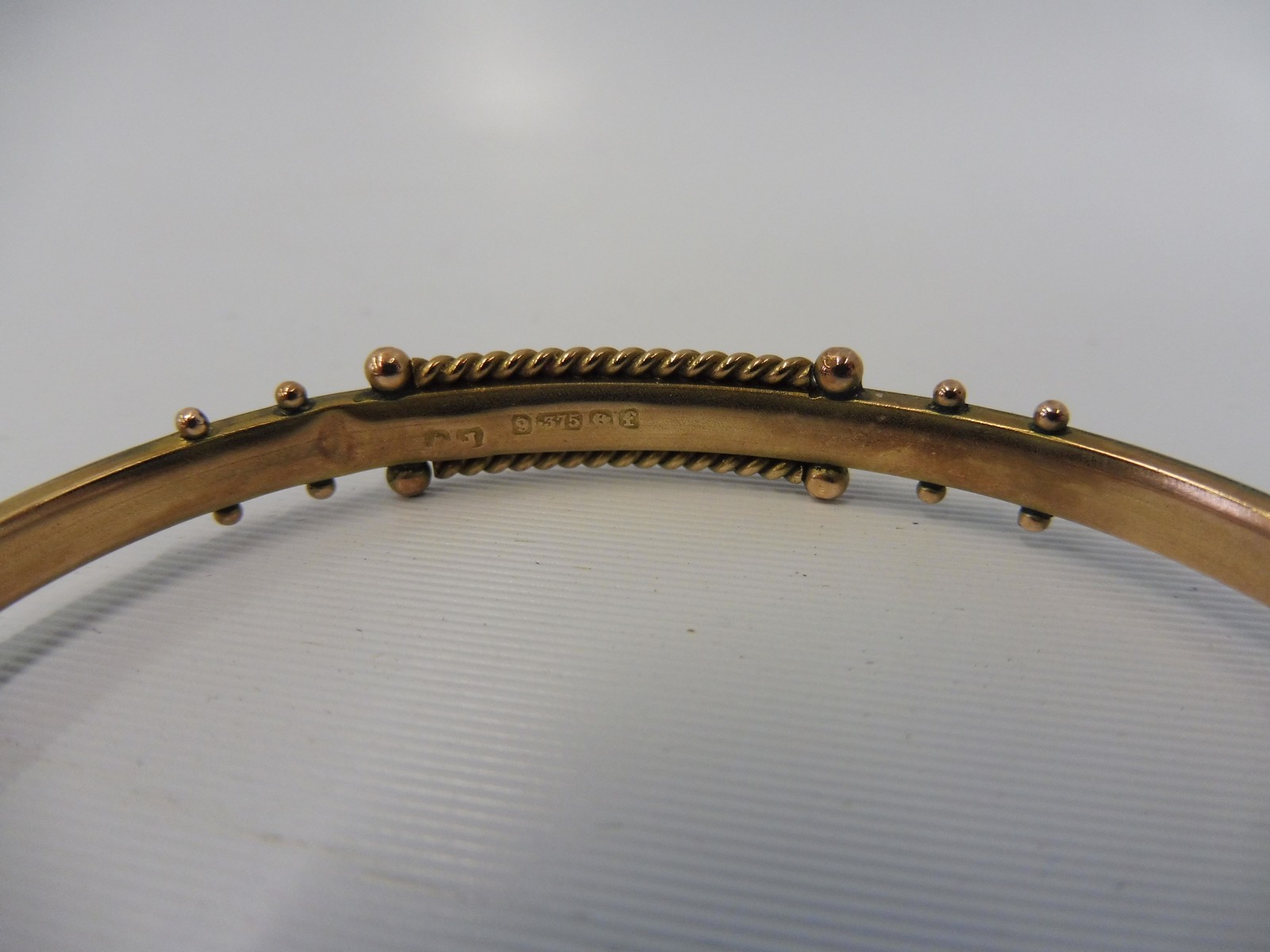 A 9ct gold bangle inset with sapphires and a seed pearl, weight approx. 8g. - Image 2 of 2