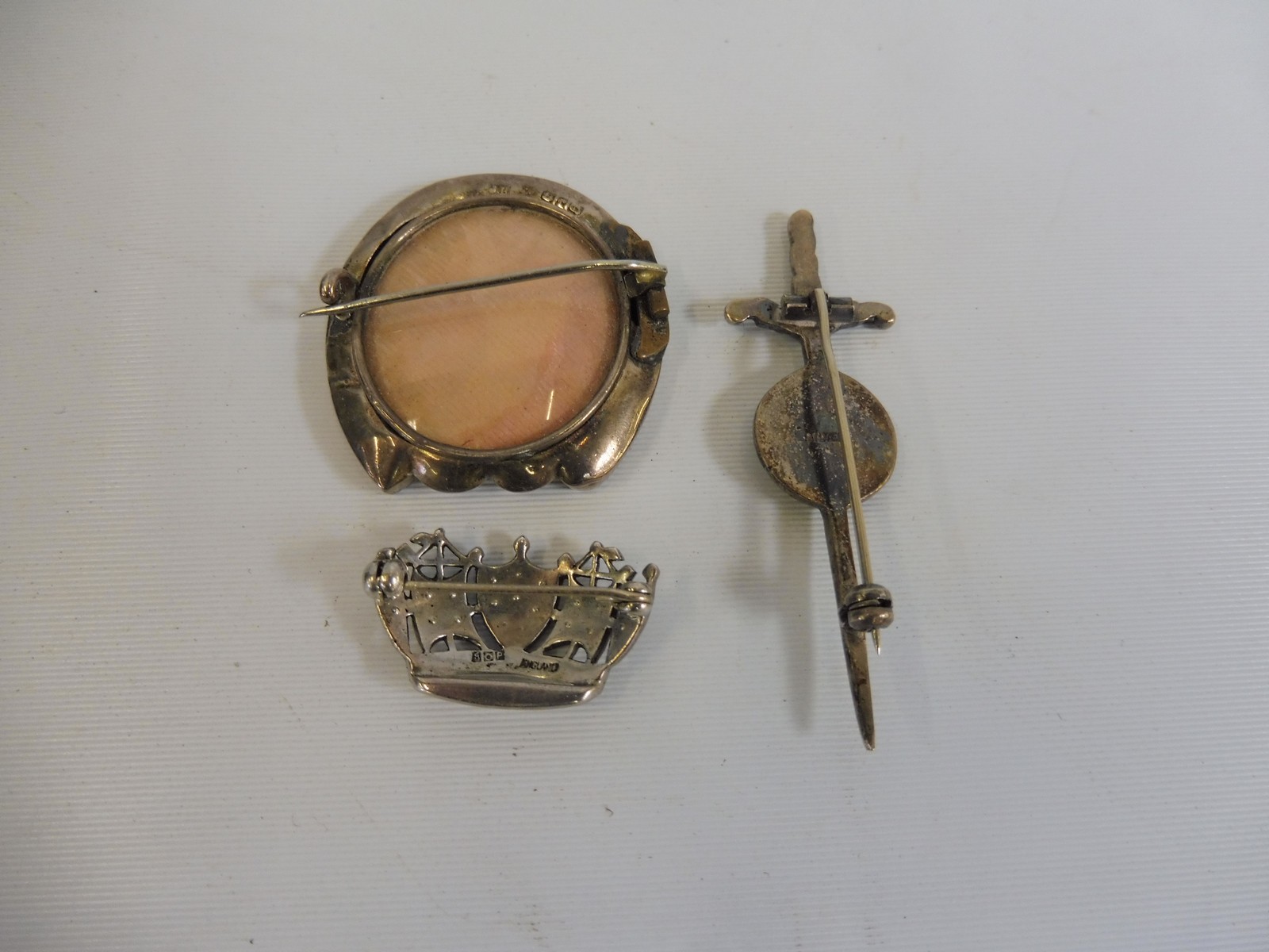 A silver horseshoe shaped brooch,a silver sword and shield brooch and one other - Image 2 of 2