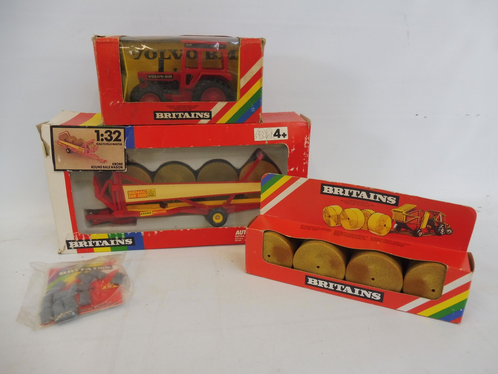 A boxed Britains rainbow box farm tractor Volvo BN and a round bale wagon and a 1743 round hay bales