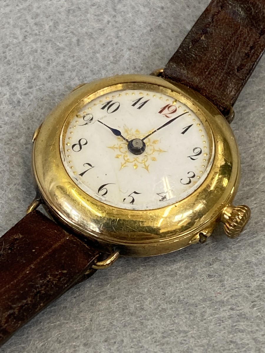 An 18ct gold ladies wristwatch with white enamel dial, on a leather strap.
