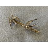 A gold (unmarked) bar brooch surmounted by a pair of diamond encrusted swallows in flight with