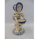 A French faience double sided back to back figure of a lady carrying a bowl, possibly Quimper.