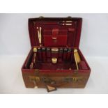 A brown leather travelling vanity case containing an assortment of silver topped glass bottles and