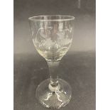 A Georgian drinking glass with a finely engraved bowl above a square foot.
