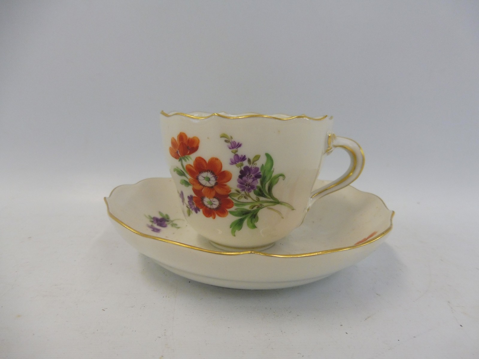 A 19th Century Continental porcelain cup and saucer, in the manner of Meissen, blue crossed swords