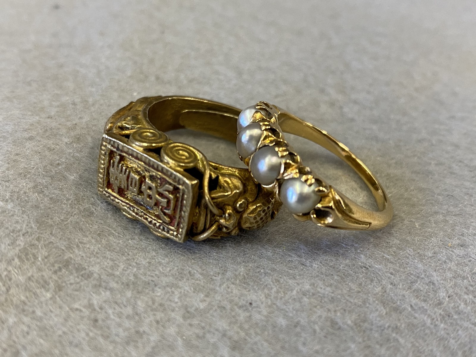 A yellow metal (probably gold) ring set with four pearls plus an unusual Asian ring, heavily