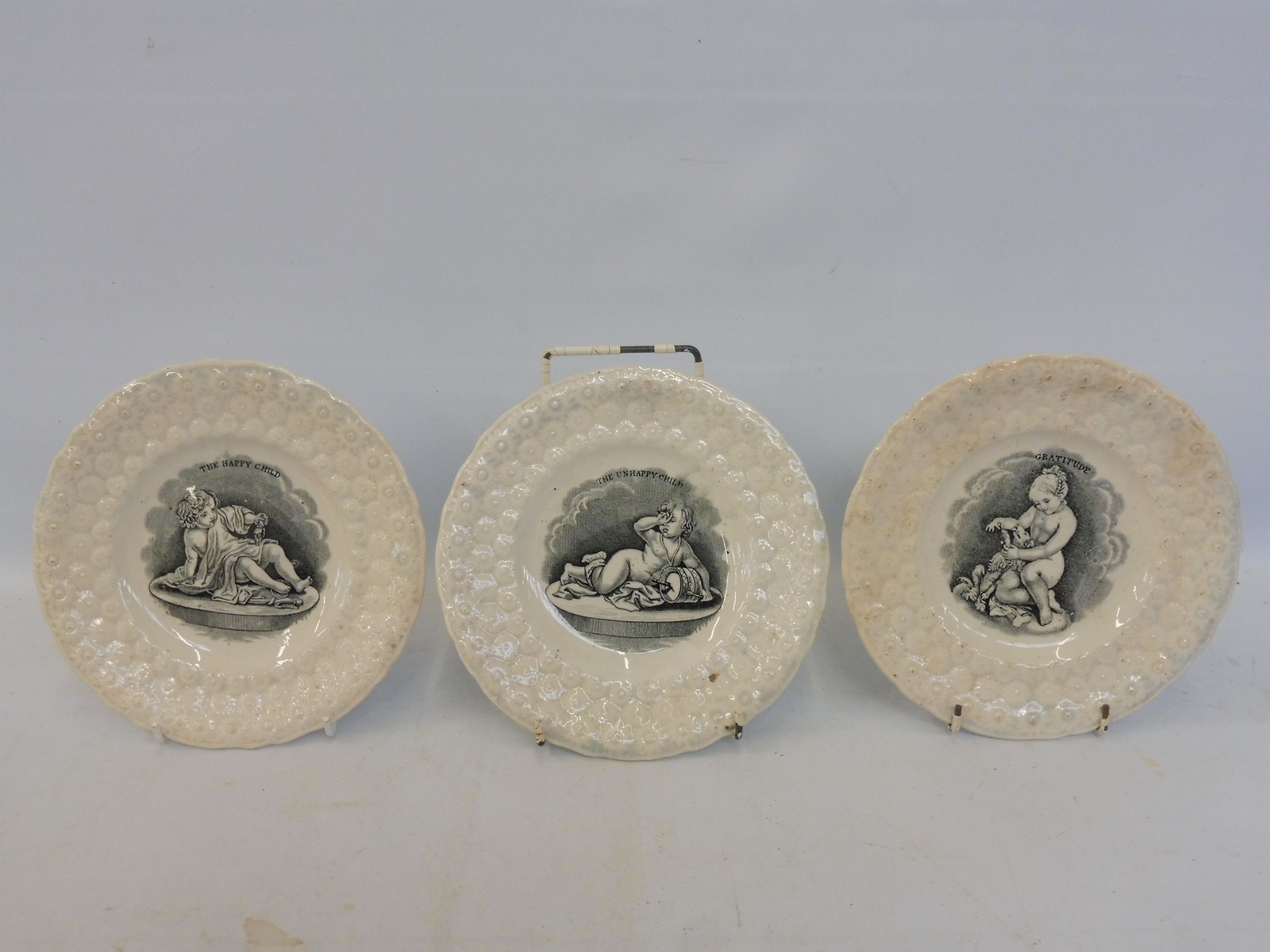 A set of three Victorian child's plates: The Unhappy Child, The Happy Child and Gratitude.
