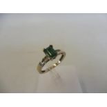 An 18ct gold ring set with a central emerald flanked by diamonds, marked .750.