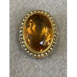 A 9ct gold scarf clip set with a large faceted citrine surrounded by a ring of seed pearls.