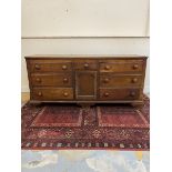 A George III oak dresser base of seven drawers, central cupboard and canted corners, raised upon