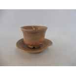 A Chinese celadon miniature cup and saucer in red tint glaze.