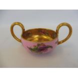 A Coalport porcelain two handled cup with gilded decoration and painted floral sprigs.