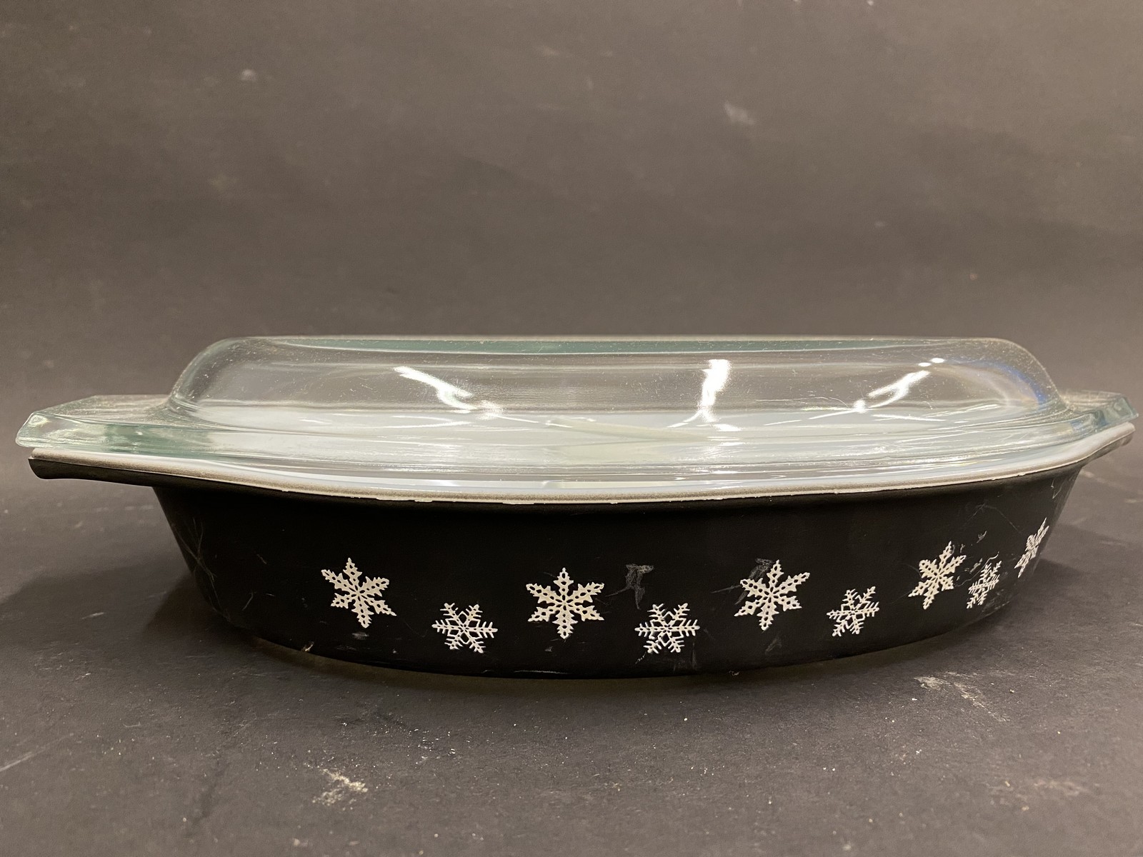 A black pyrex oval serving dish with a clear glass lid.