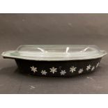 A black pyrex oval serving dish with a clear glass lid.