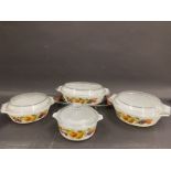 A set of four Pyrex serving dishes each with clear lids and decorated with fruit.