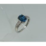 A 9ct white gold Dress Ring, set with a central blue coloured stone, the shoulders with three rows