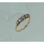 A graduated five stone diamond Ring, in an 18ct yellow gold scroll mount, Size M.