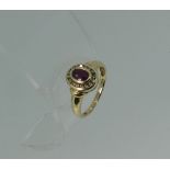 A 9ct yellow gold Ring, the circular front set with a central facetted oval ruby, with a surround of