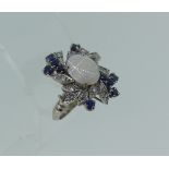 An 18k white gold Dress Ring, the centre set with an oval opal, with a surround of petals, each with