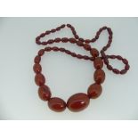 A 'Cherry' Amber Necklace, formed of graduating beads, largest bead 30mm, concealed screw bead