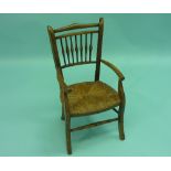An early 20th century child's spindle-back Armchair, with rush seat, the shaped legs joined by