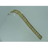 A 9ct gold flexible link Bracelet, the rectangular plaque links joining to form a scrolling rose and