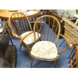 A pair of Ercol blonde elm Stick Back Arm Chairs, each with six sticks and with floral cushion pads,