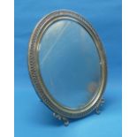 A Continental silver (800) mounted oval Easel Mirror, with moulded foliate rim and scrolling