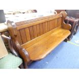 An antique stained pine Pew, with planked back and shaped side supports comprising ecclesiastical